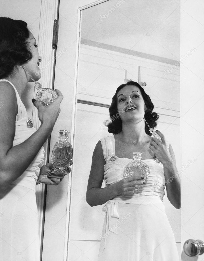 Woman applying perfume at mirror