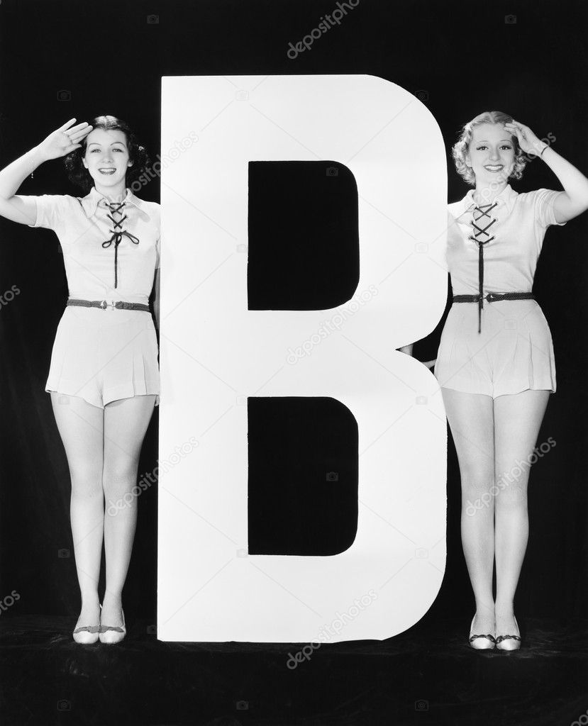 Two women saluting with huge letter B