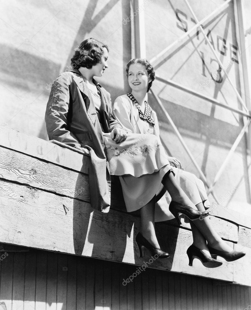 Two women sitting together on scaffolding