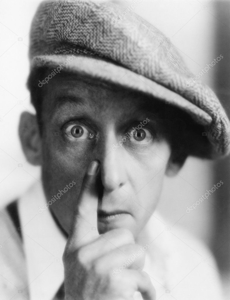 Man with cap putting his finger to nose