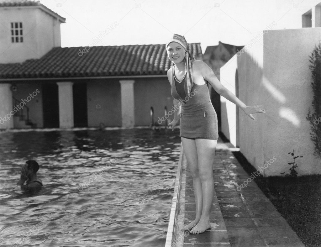 Woman next to a pool in her swimming cap and bathing suit
