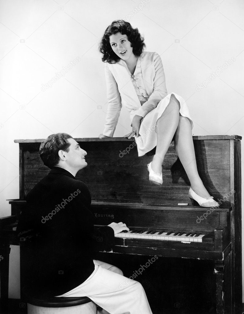 Woman singing on an upright piano with a friend playing