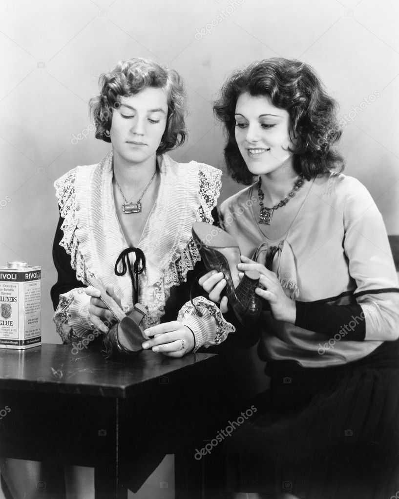 Two woman sitting together at a table repairing their shoes