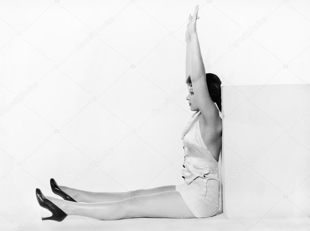 Profile of a young woman exercising against a cube