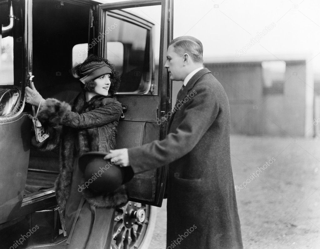 Profile of a man helping a young woman board a car
