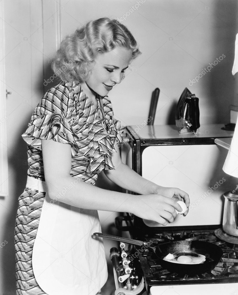 Young woman breaking an egg into a frying pan