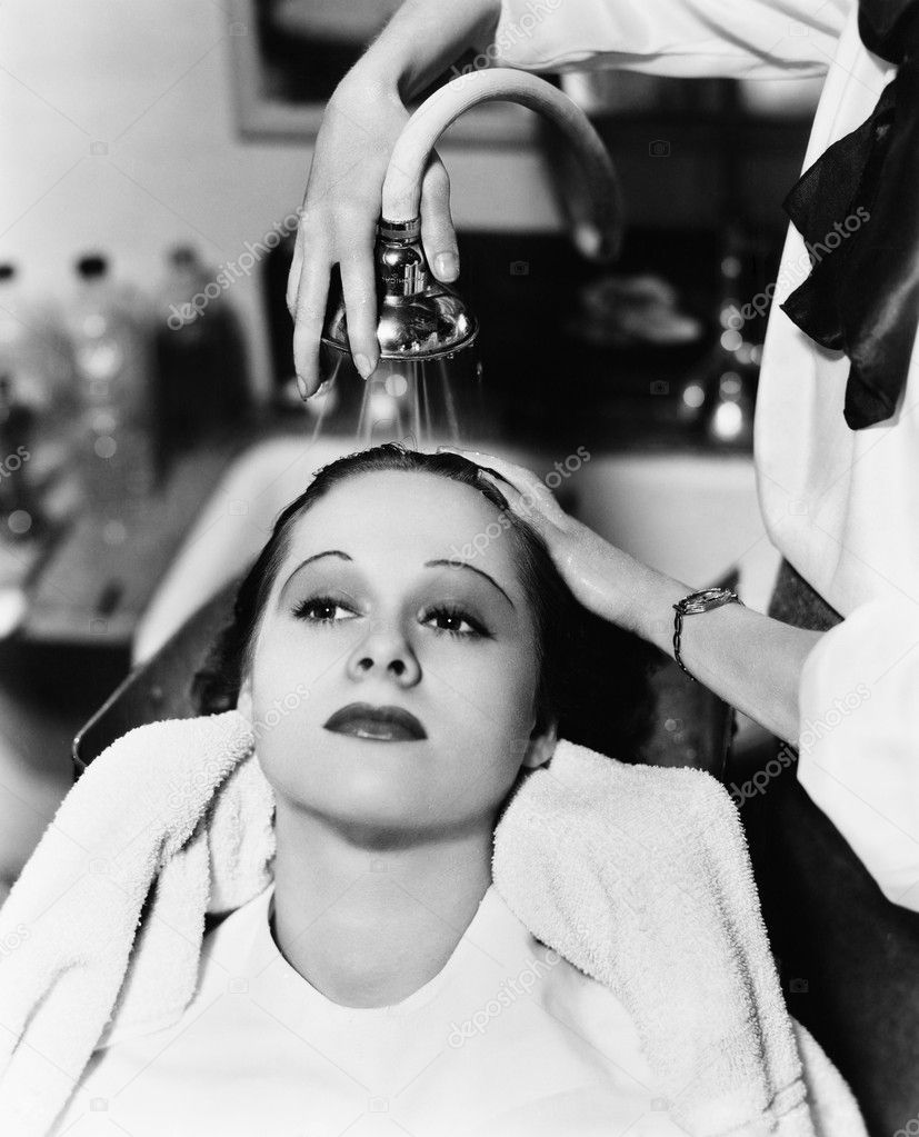 View of a female hairdresser washing hair of a young woman in a hair ...
