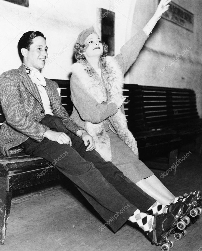 Couple wearing roller skates and sitting on a bench