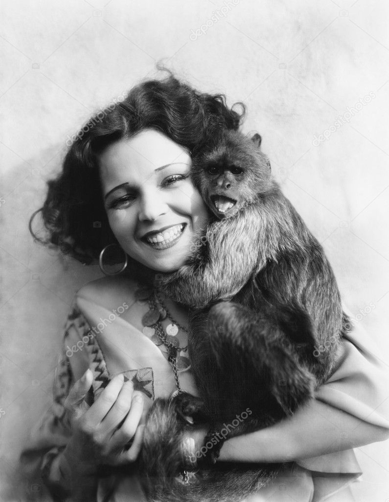 Portrait of a young woman hugging her monkey