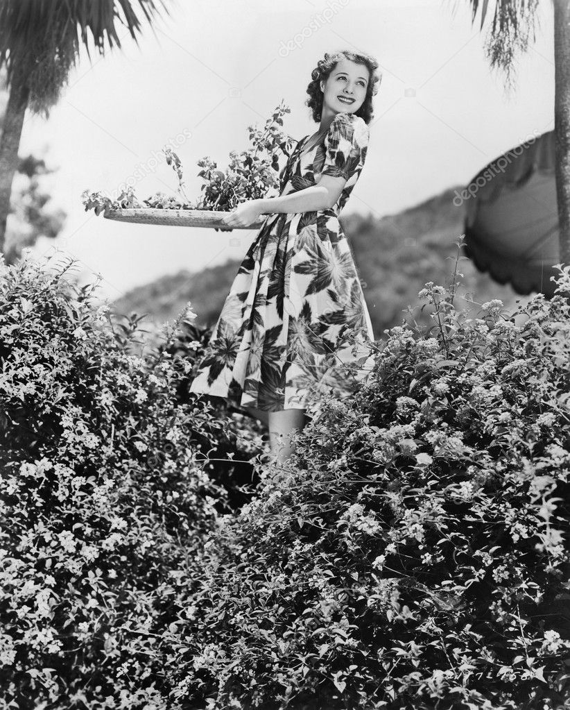 Young woman carrying a tray of Flowers in a garden