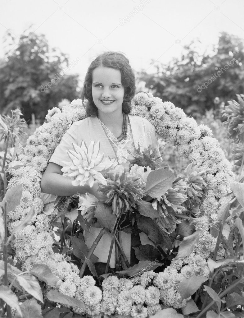 Young woman sitting in garden in a wreath of flowers