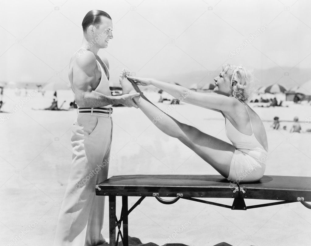 Trainer and young woman doing exercises at the beach