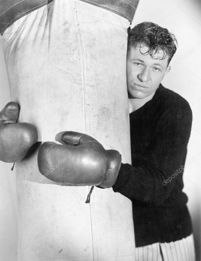Man in boxing gloves hugging the punching bag