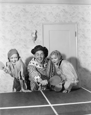 Two women and one man in a costume playing table tennis clipart