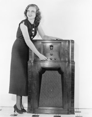 Woman next to a radio turning the knobs clipart