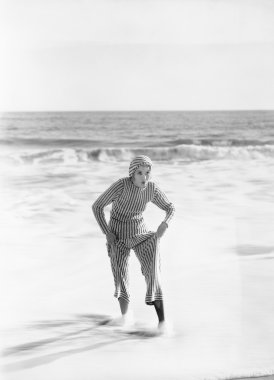 Woman in a striped suit stepping out of the ocean clipart