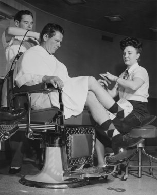 Man getting his hair cut and nails manicured clipart