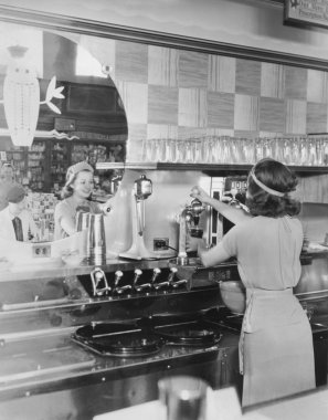 Rear view of smiling woman pouring drink from soda fountain clipart