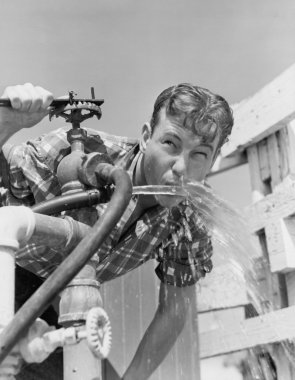 Young man drinking water from hose clipart