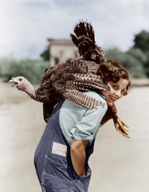 Portrait of woman with live turkey slung over shoulder clipart