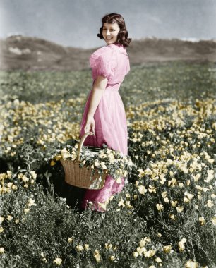 Rear view of a girl standing in a meadow holding a flower basket and smiling clipart