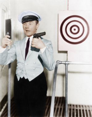 Young man looking at a mirror and aiming at a dartboard with a handgun clipart