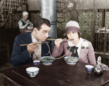 Couple sharing a noodle in a restaurant clipart