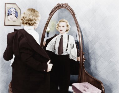 Young woman in men's clothing getting undressed in front of a mirror clipart