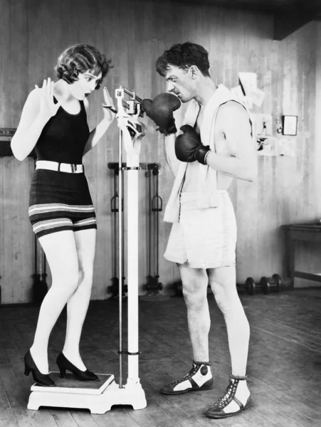 Młoda kobieta w szoku na jej wagi z mężczyzną w Rękawice bokserskie — Zdjęcie stockowe