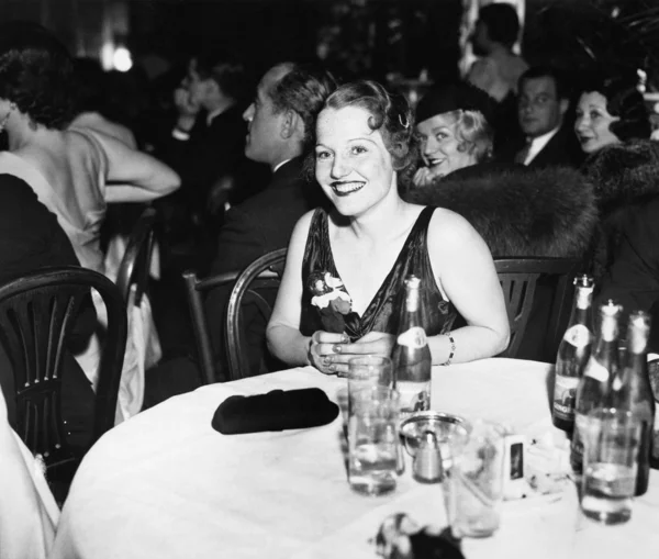 Žena sedí u stolu v klubu — Stock fotografie