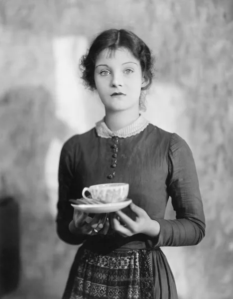 Woman standing with a cup of tea resting on her fingers — Stock Photo, Image