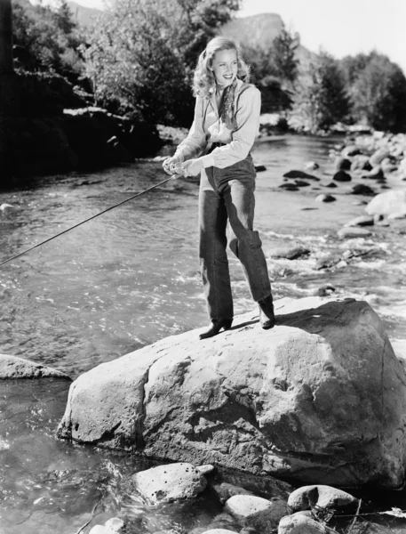 Γυναίκα να στέκεται πάνω σε ένα βράχο με ένα καλάμι ψαρέματος — Φωτογραφία Αρχείου