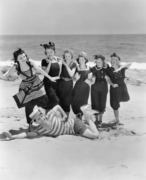 Giovane uomo con un gruppo di giovani donne in spiaggia — Foto Stock