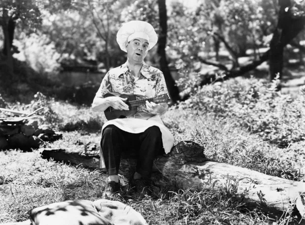 Homem com um chapéu de chefs sentado do lado de fora e jogando o yukalalee — Fotografia de Stock