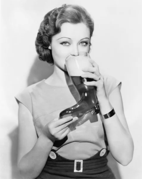 Mulher bebendo cerveja de um copo em forma de bota — Fotografia de Stock