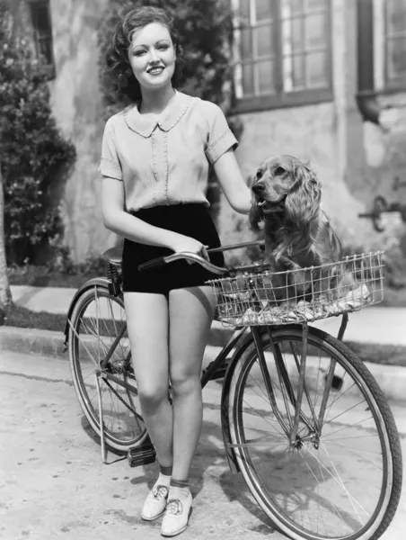 かごの中の彼女の犬と彼女の自転車の横にある女性 — ストック写真
