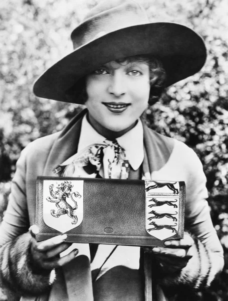 Женщина держит и показывает сумочку с фамильным гербом — стоковое фото