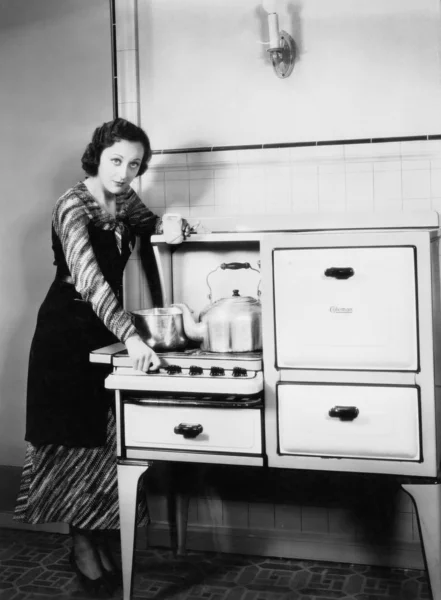 Mujer junto a su estufa en la cocina —  Fotos de Stock