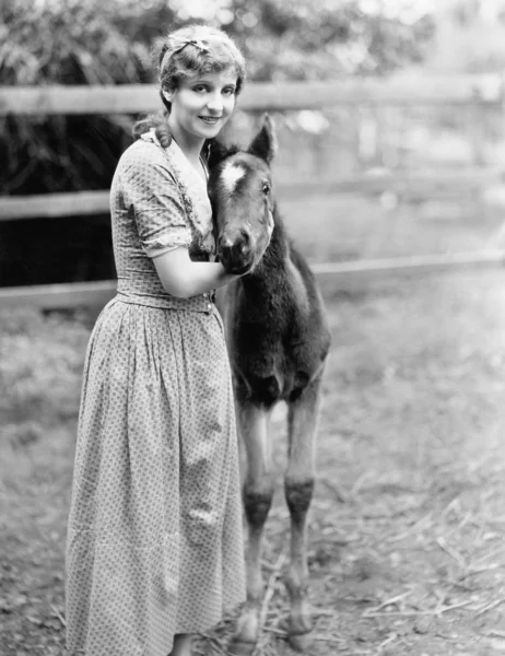 Woman standing next to a pony in a corral — Stock Photo, Image