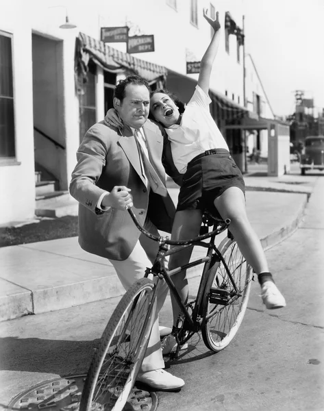Bisikletle coşkulu bir kadın dengelemeye çalışan adam — Stok fotoğraf
