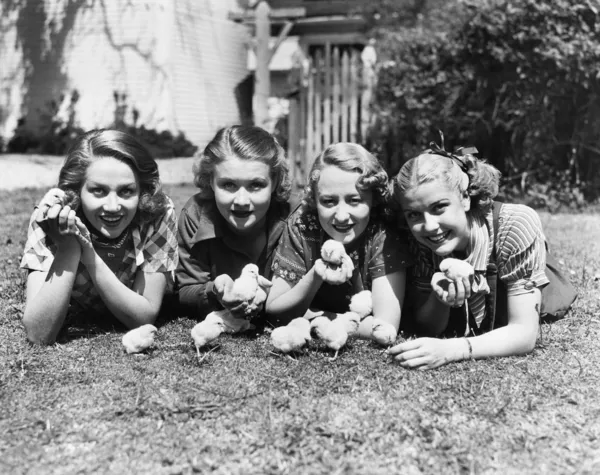 Quatro mulheres jovens deitadas lá fora com pintos de bebé . — Fotografia de Stock