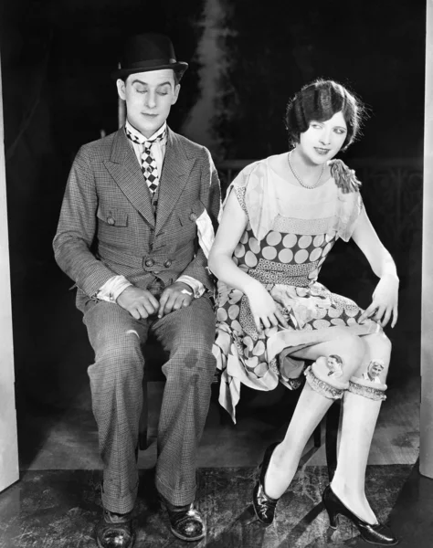 Mann blickt schäbig auf die entblößten Knie der jungen Frau neben ihm — Stockfoto