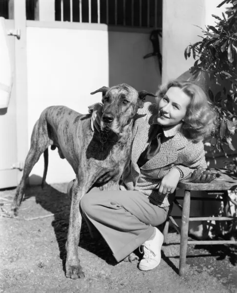 Žena ohýbání vedle její Dogu, aby mu obejmout — Stock fotografie