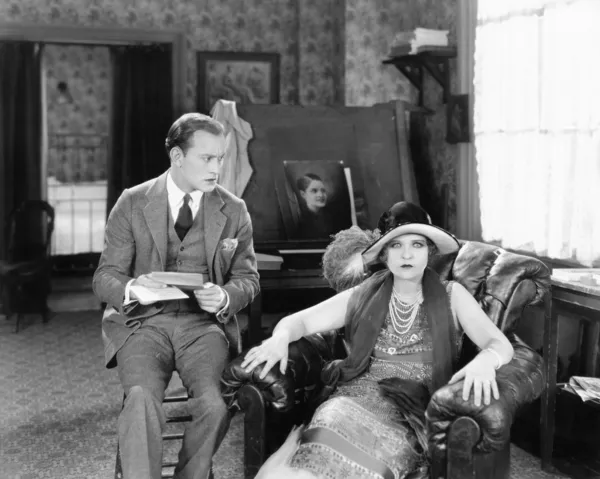 Hombre y mujer sentados en una sala de estar leyendo una carta y mirando sorprendidos —  Fotos de Stock