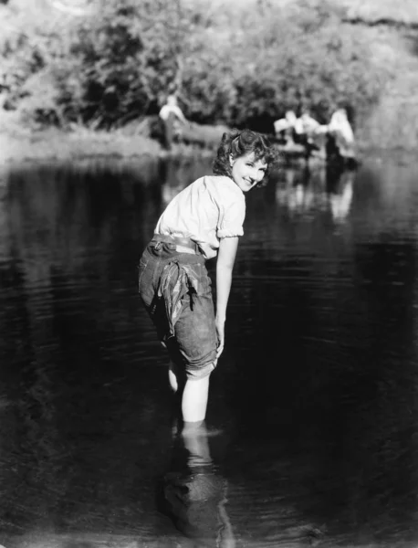 Mulher andando através da água com as calças enroladas — Fotografia de Stock