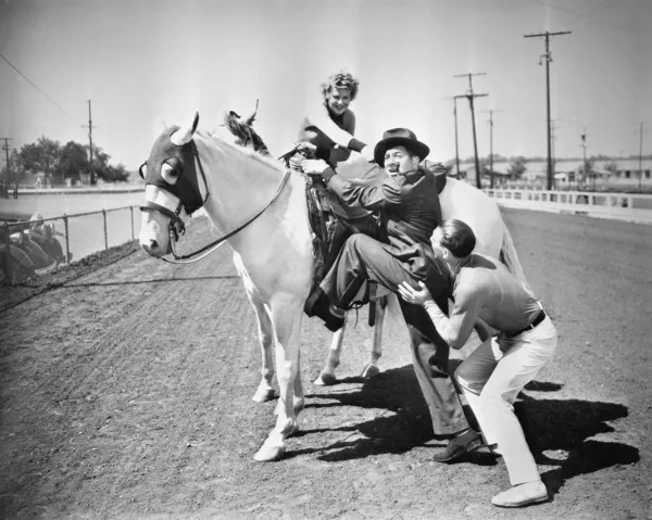 Junges Paar versucht einem Mann auf sein Pferd zu helfen — Stockfoto