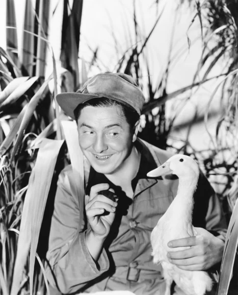 Młody człowiek uśmiechający się gospodarstwa kaczka — Zdjęcie stockowe
