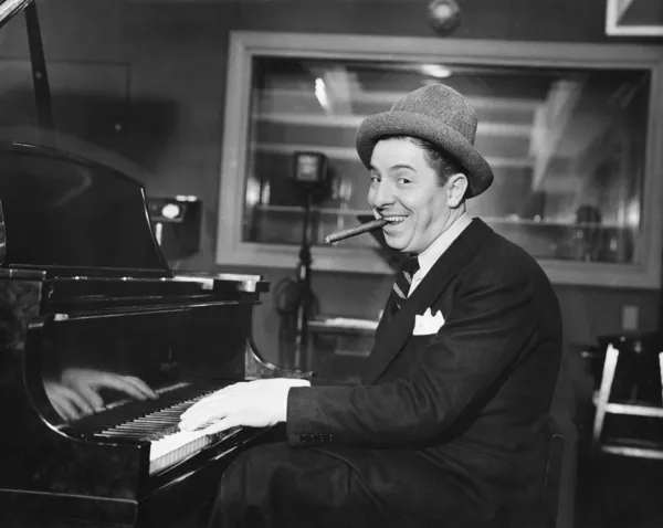 Άνθρωπος με ένα μεγάλο χαμόγελο και ένα πούρο στο στόμα του, παίζει πιάνο — Φωτογραφία Αρχείου