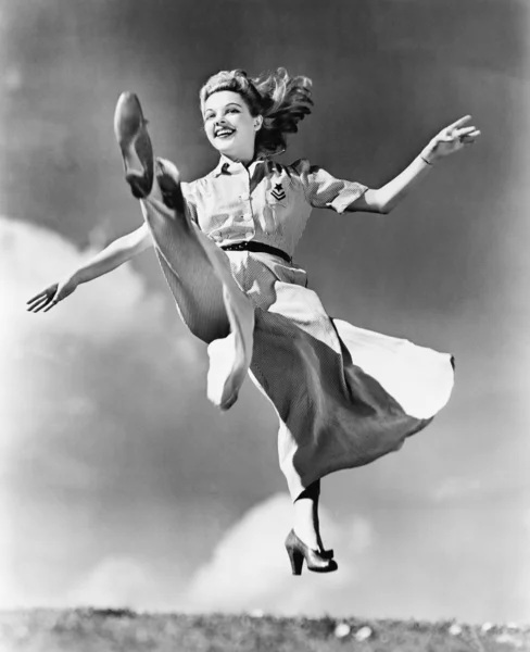 Жінка в платті, що тече, стрибає в повітрі — стокове фото