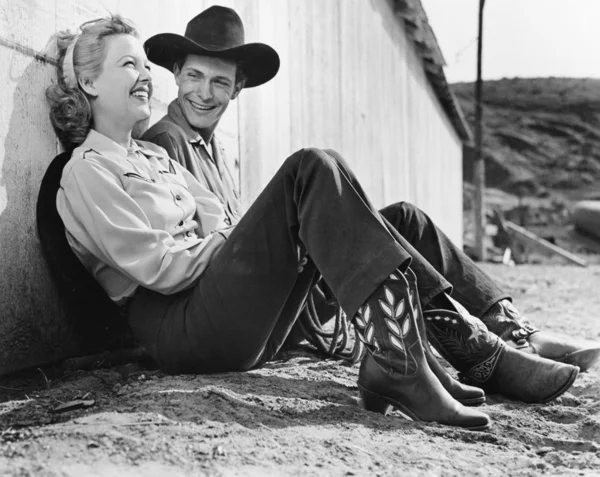 Γελώντας ζευγάρι στην δυτική ενδυμασία που κάθεται στο έδαφος — Φωτογραφία Αρχείου